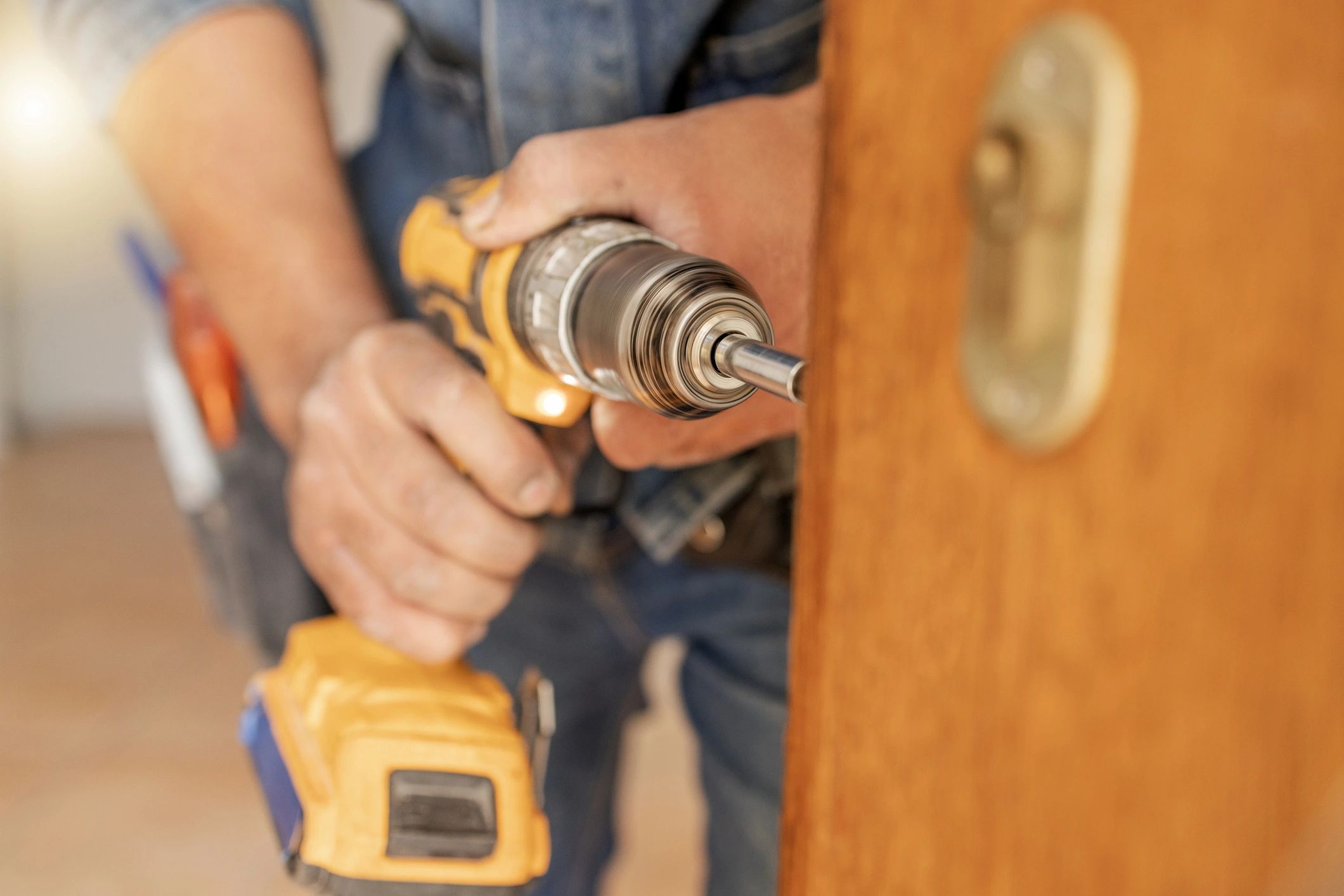 Technician repairing door hardware with a drill