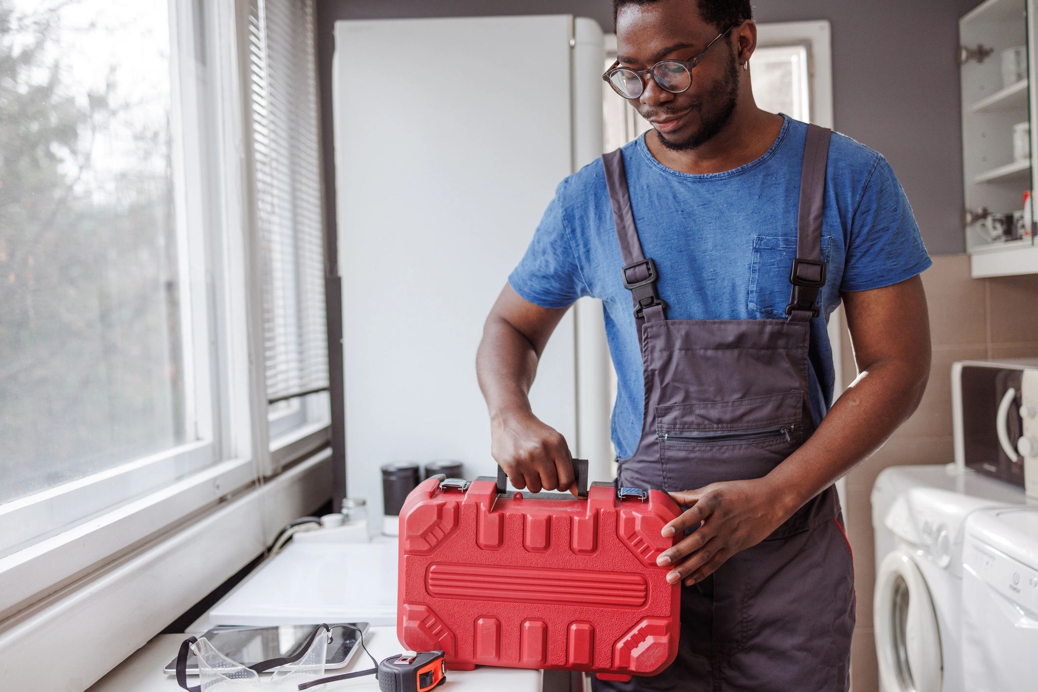 Property maintenance technician holding a toolbox in a residential kitchen